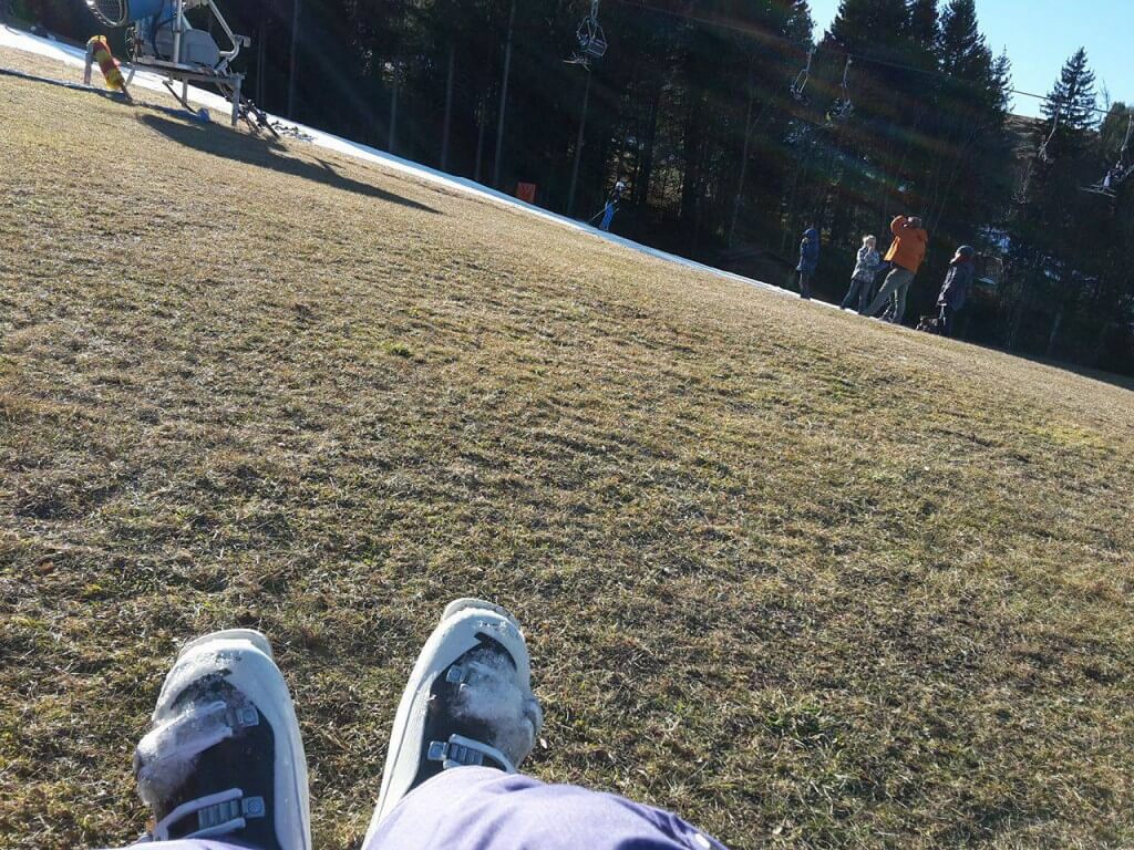 Mit Skistiefeln auf der grünen Wiese beim Sonnen
